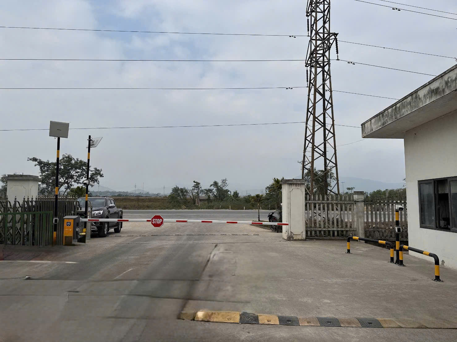 Cổng bảo vệ với thanh chắn barie tự động và biển báo dừng tại lối vào khu công nghiệp